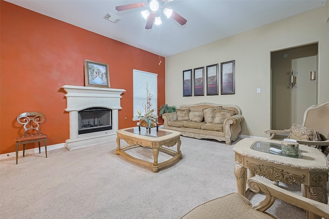 living area with baseboards, carpet flooring, a ceiling fan, a fireplace with raised hearth, and visible vents