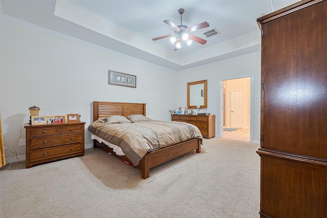 bedroom with ornamental molding, visible vents, a tray ceiling, and light colored carpet