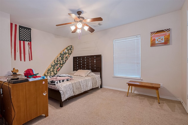 bedroom with visible vents, light colored carpet, baseboards, and ceiling fan