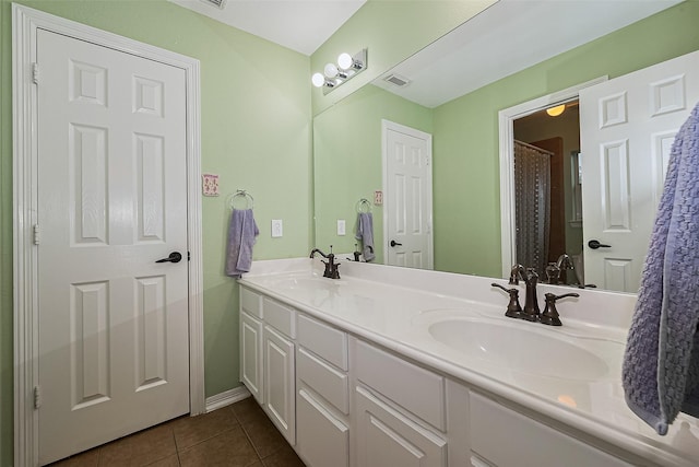 bathroom featuring tile patterned flooring, double vanity, visible vents, and a sink