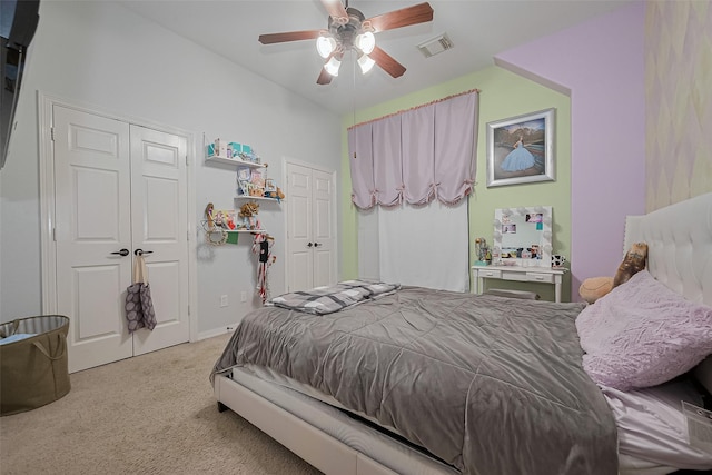 carpeted bedroom featuring ceiling fan, baseboards, visible vents, and multiple closets