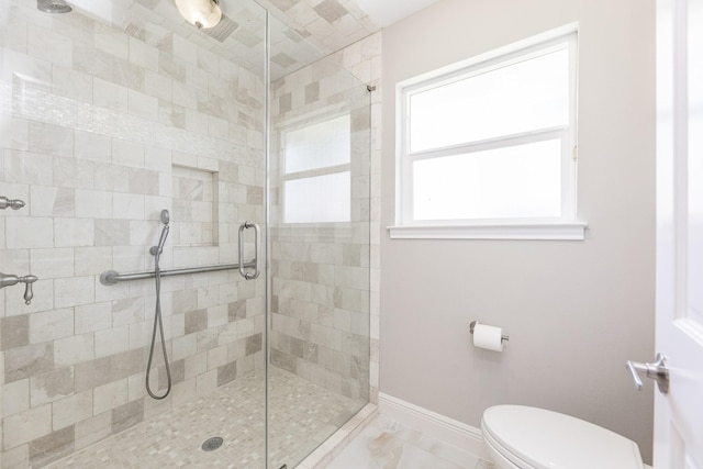 bathroom with a stall shower, toilet, baseboards, and marble finish floor