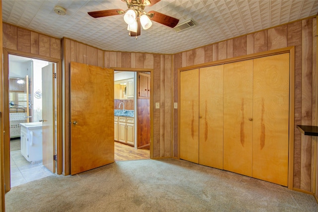 unfurnished bedroom featuring light carpet, visible vents, a closet, and connected bathroom