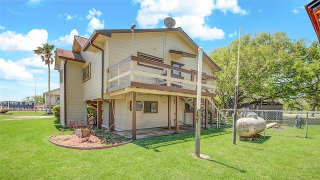 back of house featuring a deck, a patio area, fence, and a lawn