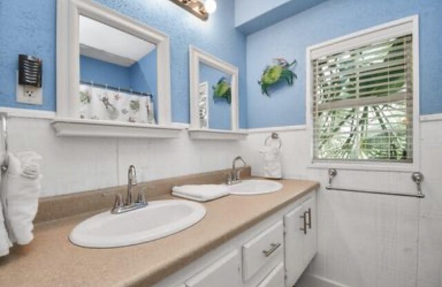 21831 Frio Dr, Galveston, TX 77554 - bathroom featuring a sink, double vanity, and wainscoting