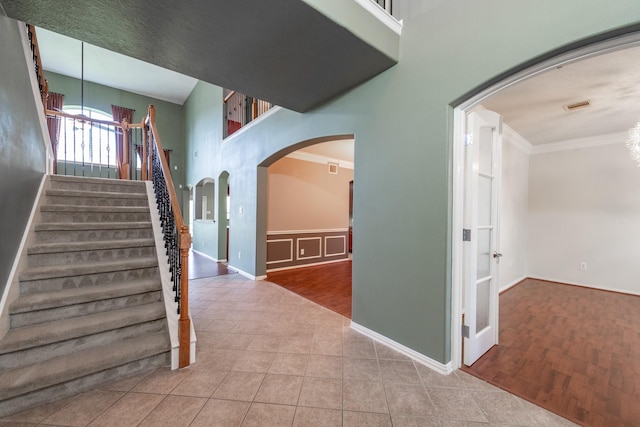 24807 Mason Trail Dr, Katy, TX 77493 - staircase with crown molding, arched walkways, visible vents, tile patterned floors, and a notable chandelier