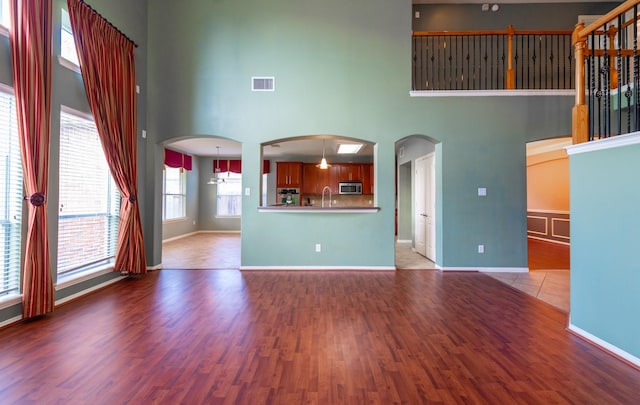 24807 Mason Trail Dr, Katy, TX 77493 - unfurnished living room featuring wood finished floors, a sink, a towering ceiling, and visible vents