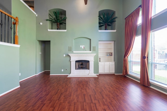 24807 Mason Trail Dr, Katy, TX 77493 - unfurnished living room featuring baseboards, wood finished floors, a fireplace with raised hearth, and a towering ceiling