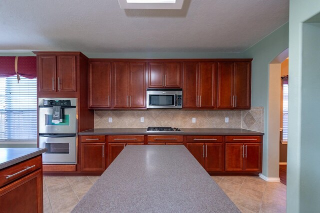 24807 Mason Trail Dr, Katy, TX 77493 - kitchen featuring arched walkways, appliances with stainless steel finishes, decorative backsplash, and light tile patterned floors