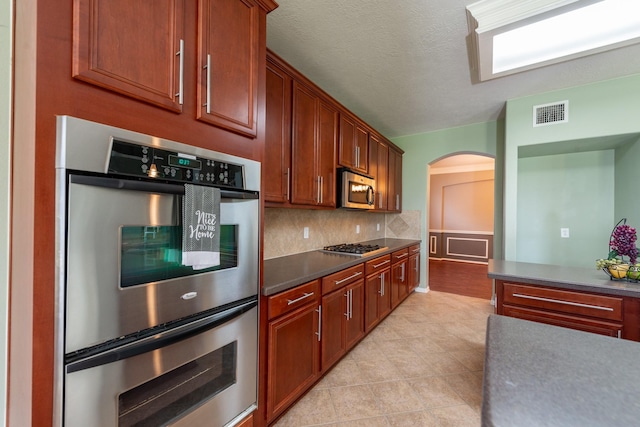 24807 Mason Trail Dr, Katy, TX 77493 - kitchen featuring tasteful backsplash, visible vents, arched walkways, appliances with stainless steel finishes, and dark countertops