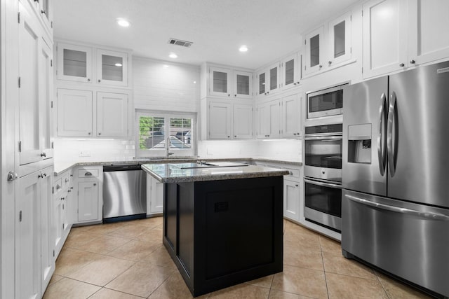 2906 Penninsula Pt, Montgomery, TX 77356 - kitchen featuring appliances with stainless steel finishes, light stone counters, light tile patterned floors, decorative backsplash, and recessed lighting