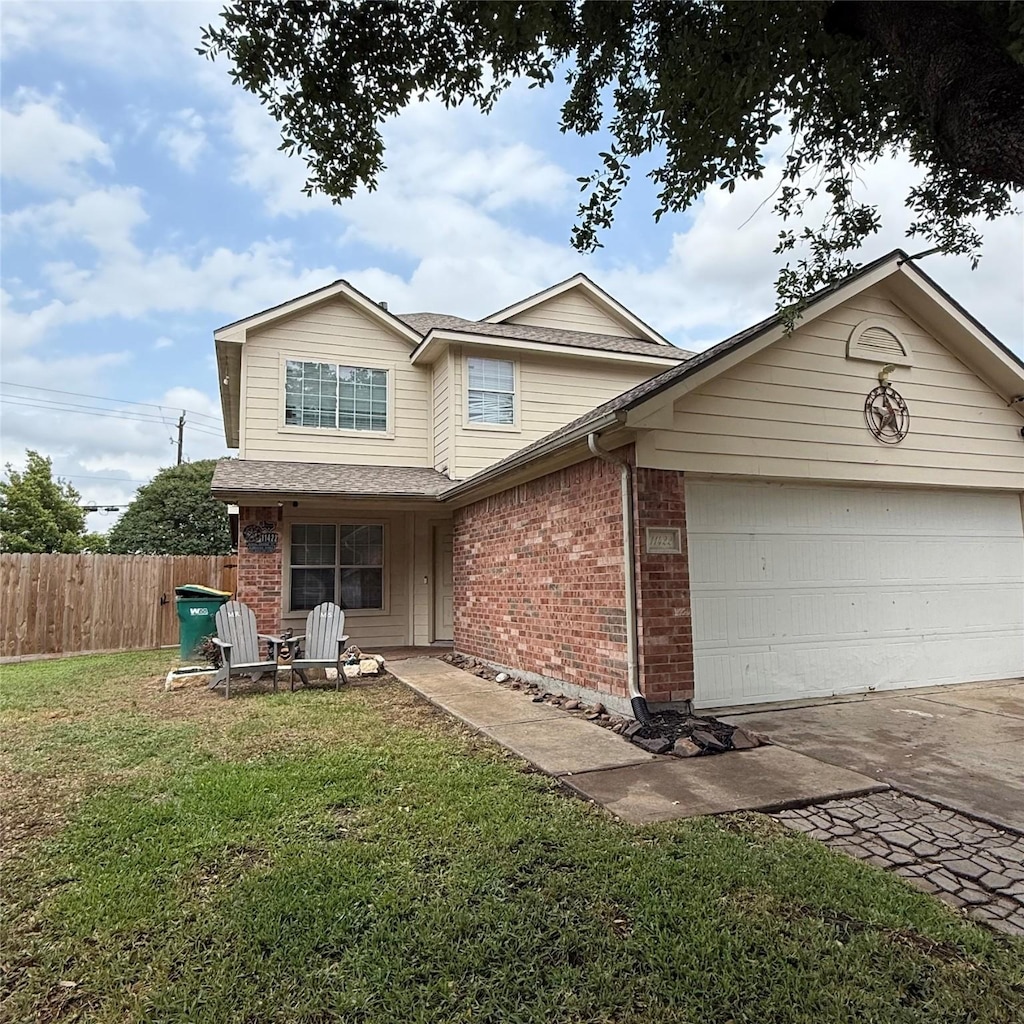 traditional-style home featuring fence, a front yard, driveway, and brick siding