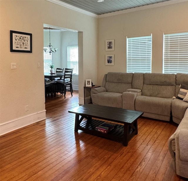 living room with hardwood / wood-style floors, a notable chandelier, baseboards, and crown molding