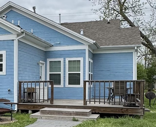 rear view of property with a deck and a shingled roof