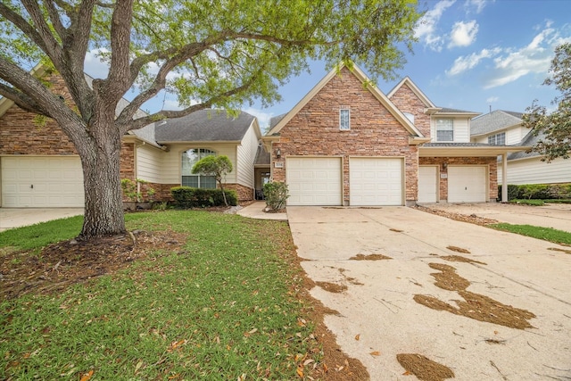 traditional-style home featuring a garage, a front yard, stone siding, and concrete driveway