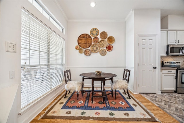 dining space with light wood-style flooring, crown molding, and baseboards