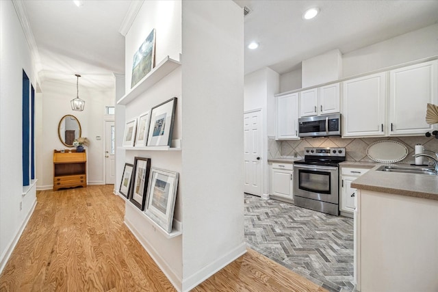 kitchen with tasteful backsplash, light wood-type flooring, white cabinets, stainless steel appliances, and a sink
