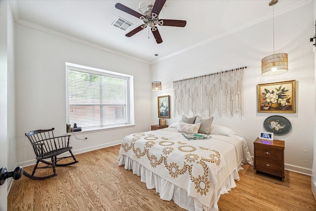 bedroom with crown molding, wood finished floors, baseboards, and visible vents