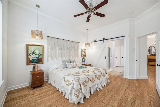 bedroom with ornamental molding, baseboards, a barn door, and light wood-style floors