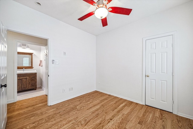unfurnished bedroom featuring light wood-style flooring, baseboards, and a sink