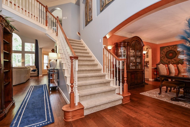 37703 Edgewater Dr, Pinehurst, TX 77362 - stairs with arched walkways, wood-type flooring, ornamental molding, baseboards, and a towering ceiling