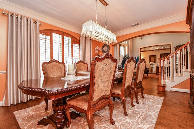 37703 Edgewater Dr, Pinehurst, TX 77362 - dining area featuring arched walkways, crown molding, stairway, a chandelier, and wood finished floors
