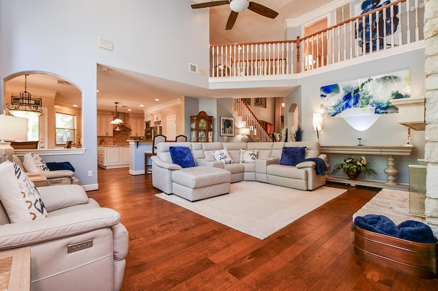 37703 Edgewater Dr, Pinehurst, TX 77362 - living room with arched walkways, a towering ceiling, a ceiling fan, dark wood-style floors, and stairs