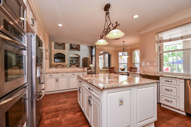 37703 Edgewater Dr, Pinehurst, TX 77362 - kitchen with a kitchen island, ornamental molding, white cabinetry, light stone countertops, and recessed lighting