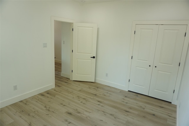 unfurnished bedroom with a closet, light wood-style floors, and baseboards