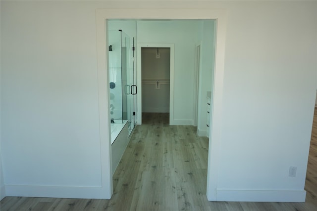 hallway with light wood-style flooring and baseboards