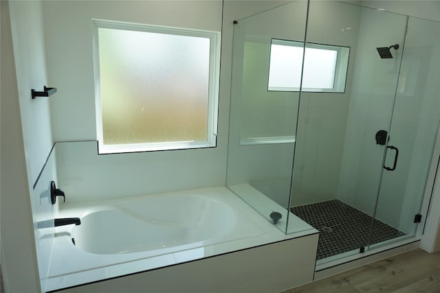 full bath featuring a shower stall, a garden tub, and wood finished floors