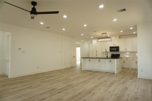 kitchen featuring a ceiling fan, black appliances, visible vents, light wood finished floors, and a sink