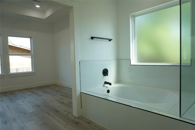 full bathroom with a garden tub, wood finished floors, and baseboards