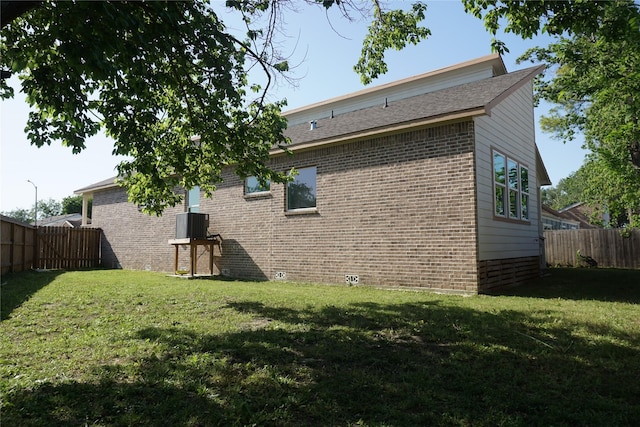 rear view of property with a yard, brick siding, and a fenced backyard