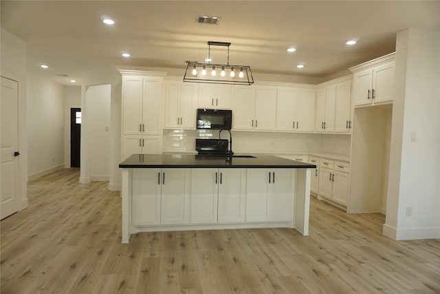 kitchen with a sink, black microwave, and white cabinets