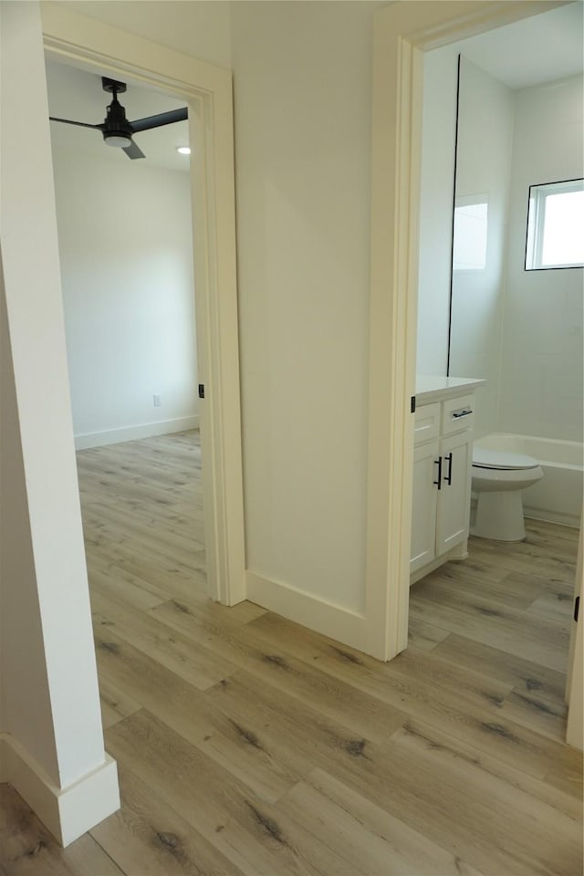 corridor featuring light wood-style flooring and baseboards
