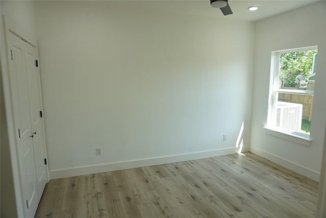empty room featuring ceiling fan, light wood-style floors, and baseboards