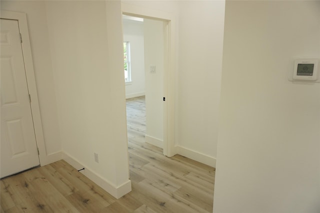 hall featuring light wood-style floors and baseboards