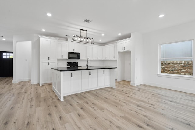 6319 Ivyknoll Dr, Houston, TX 77035 - kitchen featuring black microwave, dark countertops, range, white cabinets, and light wood-style flooring