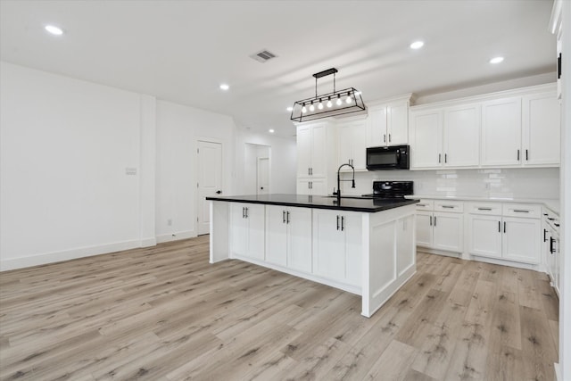 6319 Ivyknoll Dr, Houston, TX 77035 - kitchen with black microwave, range, light wood-type flooring, white cabinets, and recessed lighting
