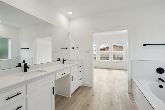 6319 Ivyknoll Dr, Houston, TX 77035 - bathroom featuring double vanity, a bathtub, wood finished floors, and recessed lighting