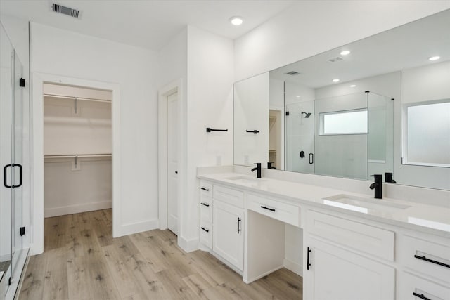 6319 Ivyknoll Dr, Houston, TX 77035 - bathroom featuring a shower stall, wood finished floors, double vanity, a walk in closet, and recessed lighting
