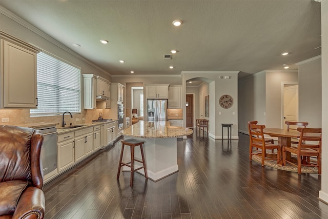 271 Spotted Saddle Ct, The Woodlands, TX 77382 - kitchen with a center island, a sink, arched walkways, stainless steel appliances, and light stone countertops