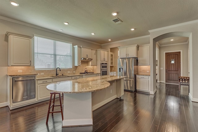 271 Spotted Saddle Ct, The Woodlands, TX 77382 - kitchen with a kitchen bar, arched walkways, a sink, and stainless steel appliances