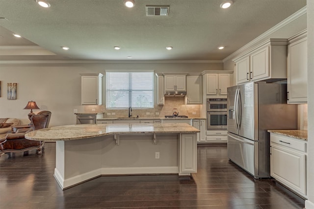 271 Spotted Saddle Ct, The Woodlands, TX 77382 - kitchen featuring a kitchen bar, ornamental molding, a sink, stainless steel appliances, and dark wood-style floors
