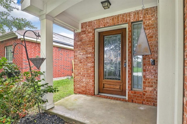 view of exterior entry featuring brick siding