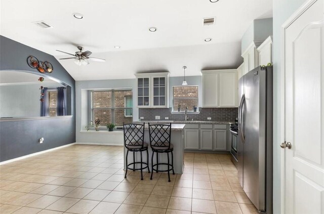 kitchen with tasteful backsplash, a kitchen breakfast bar, a kitchen island, visible vents, and stainless steel appliances