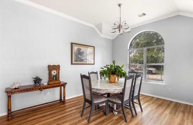 dining room with visible vents, wood finished floors, an inviting chandelier, and lofted ceiling