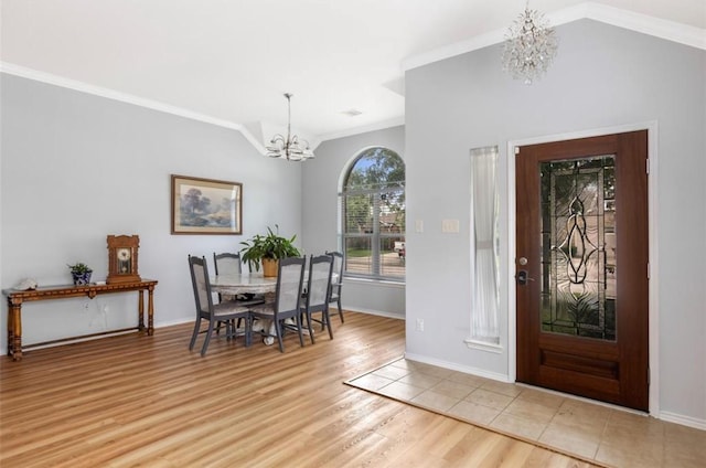 foyer entrance featuring baseboards, light wood-type flooring, a chandelier, crown molding, and vaulted ceiling