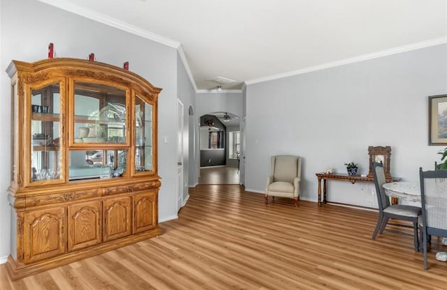 living area with crown molding, light wood finished floors, and baseboards